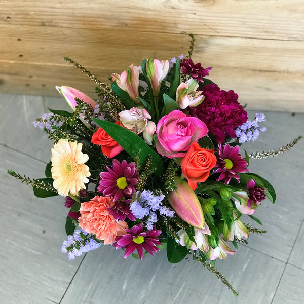 Frida is a colourful, compact arrangement of mixed blooms in shades of bright pinks, deep mauves, soft blues, lemon and a little pop of cream, expertly arranged by Enoggera Flowers in a glass cube vase. Our Frida arrangement is available for delivery to most Brisbane suburbs, or for pick up at our store in Enoggera
