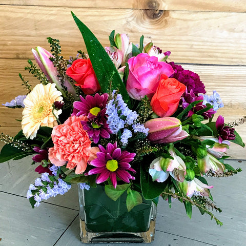 Frida is a colourful, compact arrangement of mixed blooms in shades of bright pinks, deep mauves, soft blues, lemon and a little pop of cream, expertly arranged by Enoggera Flowers in a glass cube vase.   Our Frida arrangement is available for delivery to most Brisbane suburbs, or for pick up at our store in Enoggera 